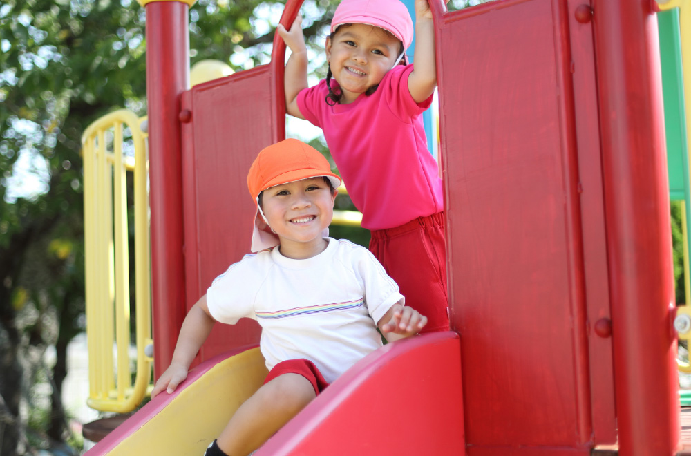写真：滑り台の上で笑顔を見せる園児たち